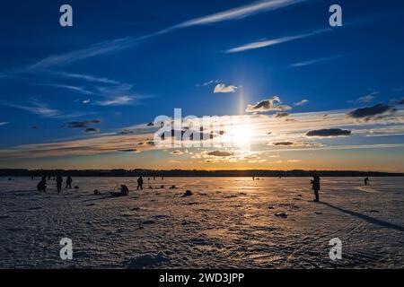 silhouettes d'un groupe d'hommes pêcheurs sur la pêche hivernale sur la glace du lac le matin contre le beau lever du soleil Banque D'Images