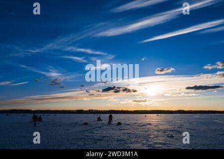 silhouettes d'un groupe d'hommes pêcheurs sur la pêche hivernale sur la glace du lac le matin contre le beau lever du soleil Banque D'Images