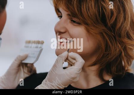 Un dentiste expérimente de nouvelles nuances de dents pour prothèses dans un cabinet dentaire, mettant en valeur la précision et l'innovation dans les soins dentaires Banque D'Images