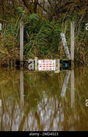 Niveau élevé de la rivière Waveney à Beccles, Suffolk, Angleterre après de fortes pluies, couvrant presque le panneau 'Private No Mooring' Banque D'Images