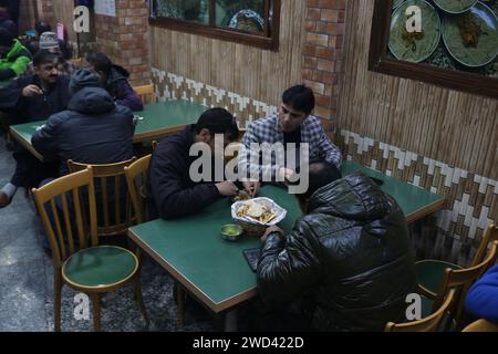 Srinagar Cachemire, Inde. 18 janvier 2024. Les clients mangent Harissa (nourriture traditionnelle cachemirienne) un matin froid à Srinagar. Harissa est une recette unique de mouton ancienne préparée pendant les hivers au Cachemire. Il est principalement disponible dans les heures du matin fait de mouton en particulier de moutons. Le mouton est d'abord cuit à température douce et tous les os sont extraits pour le rendre désossé. Le mouton est ensuite mélangé avec de la farine de riz, de l'eau et des épices variées et est remué constamment jusqu'à ce qu'il devienne croustillant. Les gens apprécient surtout ce plat avec du pain cuit au four. Le 18 janvier 2024, Srinagar Cachemire, Inde. (Crédit Banque D'Images