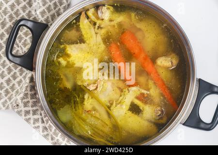 Dans une casserole en métal, le bouillon de poulet est mijoté avec des morceaux de poulet et des légumes. Banque D'Images