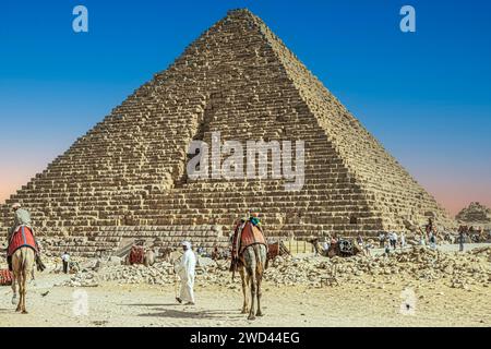 Nécropole de Gizeh, Égypte - 26 avril 2022 : Bédouins vêtus de vêtements traditionnels et touristes, devant le complexe pyramidal de la nécropole de Gizeh. Banque D'Images