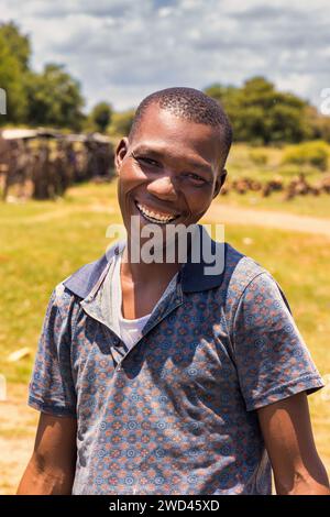 joyeux village jeune homme africain avec un grand sourire toothy dans la rue dans une journée d'été Banque D'Images