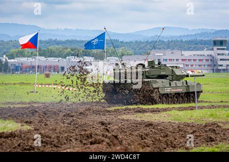 Char de l'OTAN l'Allemand a fabriqué Leopard 2 A7 conduisant devant le drapeau tchèque et le drapeau de l'OTAN sur un champ boueux en Europe pendant l'opération de jeu de guerre. Banque D'Images