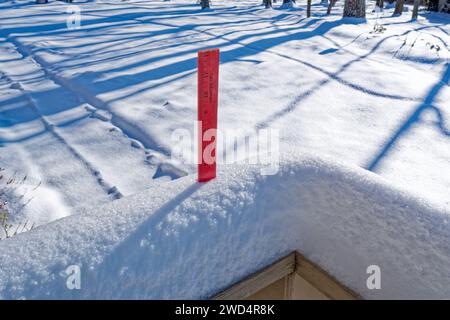 Une règle mesurant la chute de neige de 5' sur une vue rapprochée de garde-corps de pont avec de la neige sur le sol sur une journée ensoleillée en janvier Banque D'Images