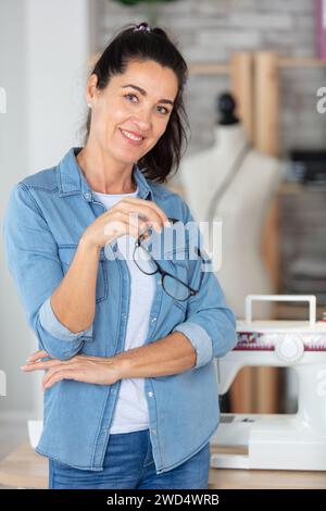 belle aiguillette mature posant dans l'atelier à côté de la machine à coudre Banque D'Images