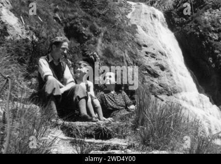 Une photo antique montre un couple marié avec un garçon posant assis sur un rebord de roche. Allemagne. Date inconnue, vers les années 1950 Banque D'Images