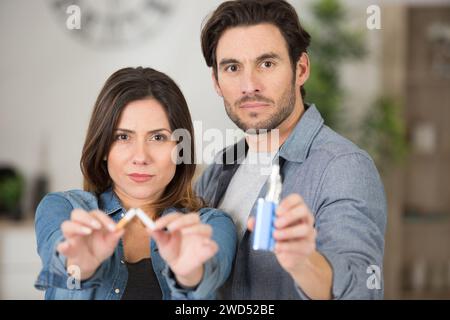 homme et femme tenant une cigarette cassée et une machine à vaporiser Banque D'Images