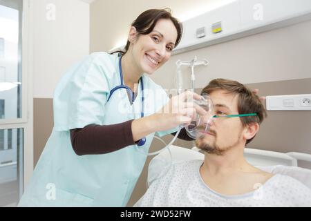 infirmière heureuse plaçant le masque à oxygène sur le patient Banque D'Images