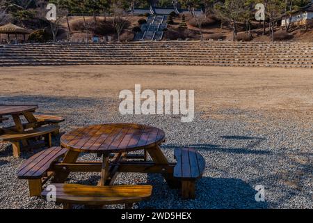 Table de pique-nique en bois avec sièges amphithéâtre et bâtiments dans le parc public en arrière-plan, Corée du Sud, Corée du Sud, Corée du Sud Banque D'Images