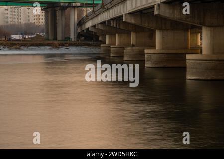 Ponts sur la rivière partiellement gelée avec des bâtiments de la ville et des arbres en arrière-plan, Corée du Sud Banque D'Images