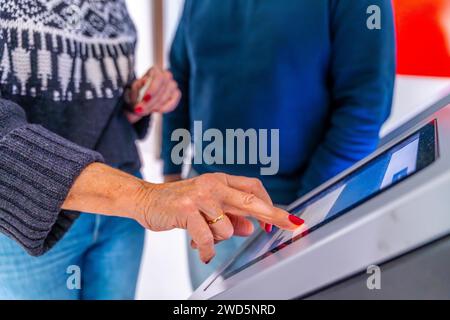 Deux patients méconnaissables utilisant une machine de rendez-vous moderne dans le hall de l'hôpital Banque D'Images