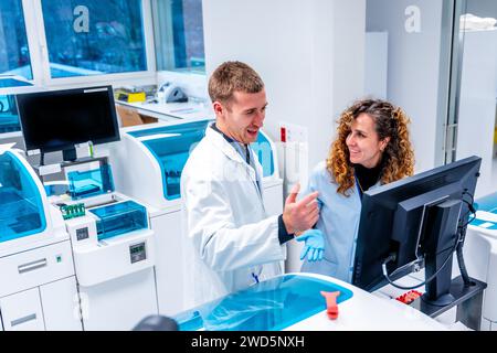 Jeunes scientifiques travaillant par ordinateur dans un laboratoire moderne d'un hôpital du domaine de la pathologie Banque D'Images