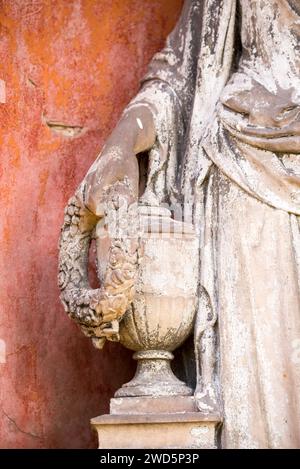 Ange blanc, main tenant une couronne de fleurs sur une urne, détail d'une statue en pierre, patiné, monument funéraire historique dans les cimetières sur Banque D'Images