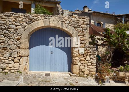 Vieux portail bleu dans un mur de pierre naturelle et jardins à la Roque-sur-Ceze, département du Gard, région Occitanie, France Banque D'Images