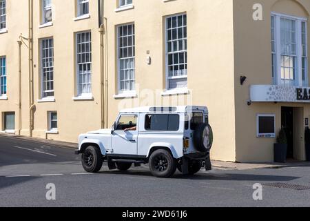 White Land Rover Defender 90 conduite à travers Swanage, Dorset, Angleterre, Royaume-Uni, 2023 Banque D'Images