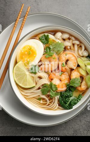 Délicieux ramen avec crevettes et baguettes sur table grise, vue de dessus. Soupe de nouilles Banque D'Images