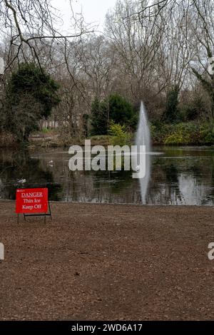 Londres, Royaume-Uni janvier 17 2024 : Frozen Lake à St James Park avec un panneau de danger et des mouettes debout sur la glace. Banque D'Images