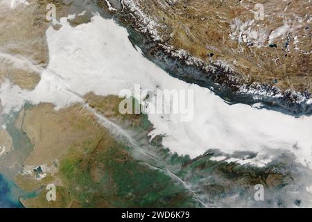 Inde. 24 décembre 2023. Décembre et janvier apportent souvent le brouillard matinal à la plaine indo-gangetique, les terres plates et fertiles qui s'étendent du Pakistan et du nord de l'Inde au Bangladesh. L'hiver 2023-2024 a suivi le modèle. Du 24 décembre 2023 au 18 janvier 2024, de grandes taches de nuages blancs bas recouvrent la région. Le MODIS (Moderate Resolution Imaging Spectroradiometer) du satellite Terra de la NASA a acquis cette image le matin du 15 janvier 2024, alors qu'un brouillard dense s'étendait d'Islamabad, au Pakistan, à Dhaka, au Bangladesh. Les îles de chaleur autour de certaines villes, y compris Delhi, Agra, moi Banque D'Images