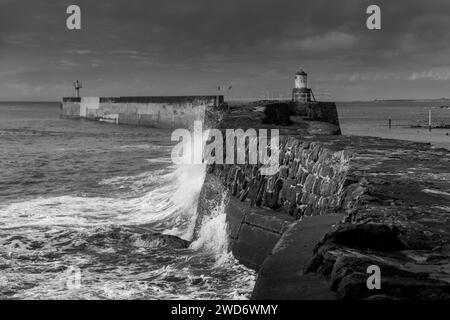 Une photo en noir et blanc d'un phare entouré de vagues qui s'écrasent Banque D'Images