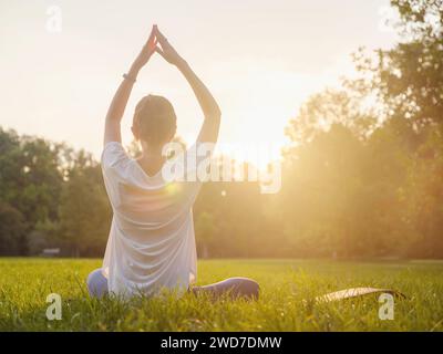 Jeune femme asiatique faisant de la méditation le matin ou le soir au parc, femme en bonne santé se détendant et pratiquant le yoga au parc de la ville. Pleine conscience, destinée, habitudes saines et concept d'équilibre Banque D'Images