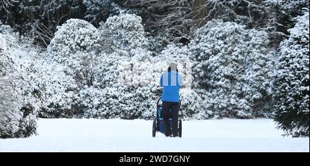 Ein Mann geht mit einem Kinderwagen auf einem mit Schnee bedeckten Weg im Stadtpark Hamburg entlang. Winterhude Hamburg *** Un homme marche avec une voiture d'enfant le long d'un chemin couvert de neige dans Hamburg City Park Winterhude Hamburg Banque D'Images