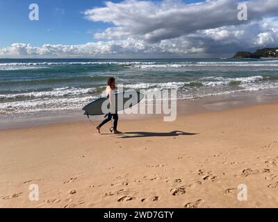 Sydney, Australie. 25 mai 2022. ILLUSTRATION - Un homme marche le long d'une plage avec sa planche de surf. Après de fortes pluies, les autorités de Sydney ont demandé à la population et aux touristes d’éviter plus de deux douzaines de plages populaires. Crédit : Carola Frentzen/dpa/Alamy Live News Banque D'Images