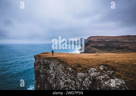 figure solitaire se dresse devant l'océan depuis le haut de la falaise. Banque D'Images