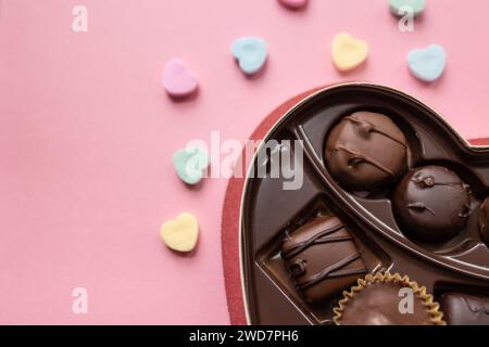 boîte de chocolats et coeurs de bonbons sur un fond rose Banque D'Images