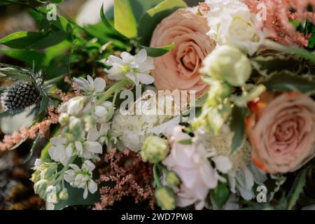 Bagues dorées pour mariée et marié nichées dans le bouquet de fleurs de mariée Banque D'Images