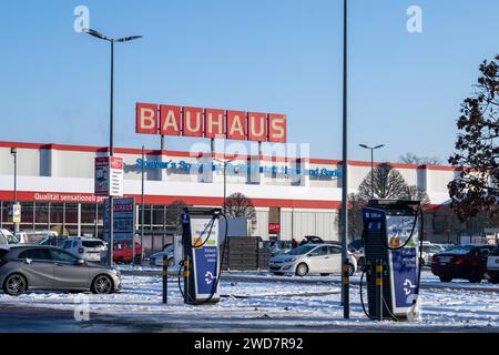 Nachhaltiges Einkaufen im Winter : BAUHAUS-Baumarkt mit Elektro-Ladestation im Schneegestöber , Deutschland, Rhénanie-Palatinat, Speyer, 19.01.2024, DAS Foto zeigt einen BAUHAUS-Baumarkt mit markantem roten Schriftzug, umgeben von einem schneebedeckten Parkplatz und mehreren Autos. Im Vordergrund ist eine Elektrofahrzeug-Ladestation sichtbar, die für das schnelle Laden wirbt. *** Achats durables en hiver BAUHAUS magasin de bricolage avec station de recharge électrique dans les neiges, Allemagne, Rhénanie-Palatinat, Speyer, 19 01 2024, la photo montre un magasin de bricolage BAUHAUS avec un lettrage rouge frappant, surrou Banque D'Images