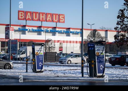 Nachhaltiges Einkaufen im Winter : BAUHAUS-Baumarkt mit Elektro-Ladestation im Schneegestöber , Deutschland, Rhénanie-Palatinat, Speyer, 19.01.2024, DAS Foto zeigt einen BAUHAUS-Baumarkt mit markantem roten Schriftzug, umgeben von einem schneebedeckten Parkplatz und mehreren Autos. Im Vordergrund ist eine Elektrofahrzeug-Ladestation sichtbar, die für das schnelle Laden wirbt. *** Achats durables en hiver BAUHAUS magasin de bricolage avec station de recharge électrique dans les neiges, Allemagne, Rhénanie-Palatinat, Speyer, 19 01 2024, la photo montre un magasin de bricolage BAUHAUS avec un lettrage rouge frappant, surrou Banque D'Images