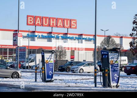 Nachhaltiges Einkaufen im Winter : BAUHAUS-Baumarkt mit Elektro-Ladestation im Schneegestöber , Deutschland, Rhénanie-Palatinat, Speyer, 19.01.2024, DAS Foto zeigt einen BAUHAUS-Baumarkt mit markantem roten Schriftzug, umgeben von einem schneebedeckten Parkplatz und mehreren Autos. Im Vordergrund ist eine Elektrofahrzeug-Ladestation sichtbar, die für das schnelle Laden wirbt. *** Achats durables en hiver BAUHAUS magasin de bricolage avec station de recharge électrique dans les neiges, Allemagne, Rhénanie-Palatinat, Speyer, 19 01 2024, la photo montre un magasin de bricolage BAUHAUS avec un lettrage rouge frappant, surrou Banque D'Images