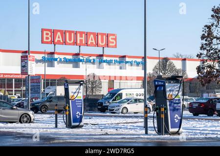 Nachhaltiges Einkaufen im Winter : BAUHAUS-Baumarkt mit Elektro-Ladestation im Schneegestöber , Deutschland, Rhénanie-Palatinat, Speyer, 19.01.2024, DAS Foto zeigt einen BAUHAUS-Baumarkt mit markantem roten Schriftzug, umgeben von einem schneebedeckten Parkplatz und mehreren Autos. Im Vordergrund ist eine Elektrofahrzeug-Ladestation sichtbar, die für das schnelle Laden wirbt. *** Achats durables en hiver BAUHAUS magasin de bricolage avec station de recharge électrique dans les neiges, Allemagne, Rhénanie-Palatinat, Speyer, 19 01 2024, la photo montre un magasin de bricolage BAUHAUS avec un lettrage rouge frappant, surrou Banque D'Images