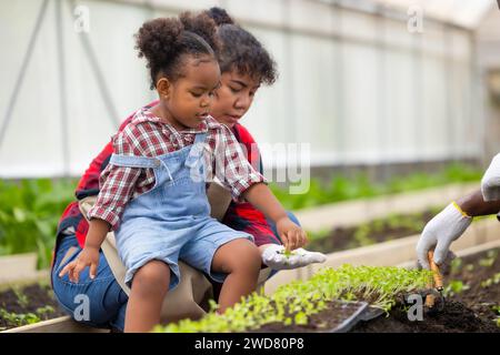 Enfant noir africain jouer planter petit arbre jardinage dans la ferme agricole avec la famille. Les enfants papa maman aiment la nature de l'agriculture oganique. Banque D'Images