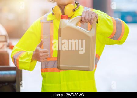 Le travailleur d'ingénieur montre le gallon de bouteille en plastique d'huile de lubrification de moteur vers le haut pour comme de bons produits de service pour la publicité d'industrie Banque D'Images