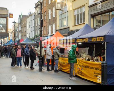 Les gens font la queue aux stands de nourriture sur Berwick Street Market à Soho, Londres, Royaume-Uni Banque D'Images