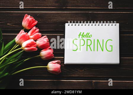 Carte de voeux avec l'inscription Hello Spring. Tulipes roses sur fond en bois Banque D'Images