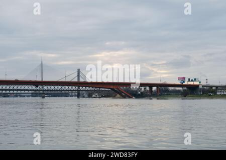 Le pont de la route de fer rouge sur la rivière Sava. Vue depuis le sol depuis la zone Waterfront par temps nuageux. Belgrade, Serbie - 07.01.2024 Banque D'Images