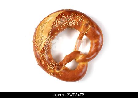 Bretzel bavarois brun doré avec une quantité généreuse de graines de sésame saupoudré dessus, d'en haut sur un fond blanc. La forme nouée du bretzel Banque D'Images