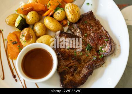 Plat dans un ancien bistro à Limoges, en France, steak de bœuf Limousin servi avec des potatos cuits au four, servi avec un bouillon léger ou de la sauce Banque D'Images