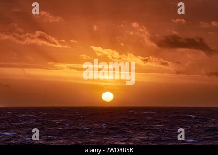 Coucher de soleil orange océan, avec nuages, océan bleu et soleil à l'horizon. Banque D'Images