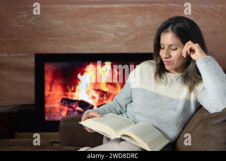 Femme aime lire un livre de son canapé à la maison. Banque D'Images