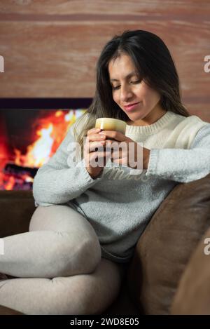 Femme apprécie un verre tout en se relaxant à la maison. Banque D'Images