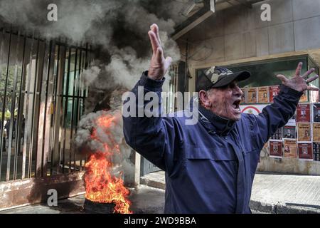 Beyrouth, Liban. 19 janvier 2024. Un déposant libanais chante un slogan devant des pneus brûlés devant une banque locale, lors d'une manifestation pour exiger l'imposition d'un calendrier pour restituer les économies des déposants. Les protestations des déposants contre les banques se sont exprimées régulièrement depuis les restrictions imposées par les banques libanaises en 2019, au début d’une crise économique sans précédent dans laquelle le Liban est encore enchevêtré. Crédit : Marwan Naamani/dpa/Alamy Live News Banque D'Images