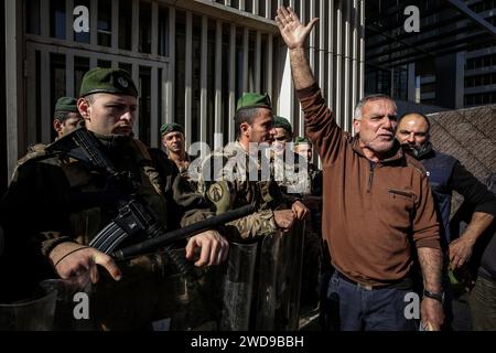 Beyrouth, Liban. 19 janvier 2024. Un manifestant crie des slogans devant des soldats libanais sécurisant une banque locale lors d'une manifestation pour exiger l'imposition d'un calendrier pour la restitution des économies des déposants. Les protestations des déposants contre les banques se sont exprimées régulièrement depuis les restrictions imposées par les banques libanaises en 2019, au début d’une crise économique sans précédent dans laquelle le Liban est encore enchevêtré. Crédit : Marwan Naamani/dpa/Alamy Live News Banque D'Images