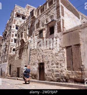 Des femmes voilées marchant avec son enfant dans une rue de Sanaa, capitale du Yémen. Les maisons sont typiques du Yémen Banque D'Images