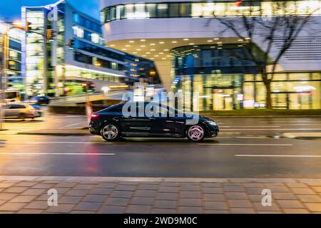 Innerstädtische Straße mit Fahrzeugen, moderne Architektur am Abend. Bewegungsunschärfe. // 17.01.2024 : Stuttgart, Bade-Württemberg, Deutschland. *** Rue de la ville avec des véhicules, architecture moderne dans la soirée Motion blur 17 01 2024 Stuttgart, Baden Württemberg, Allemagne Banque D'Images