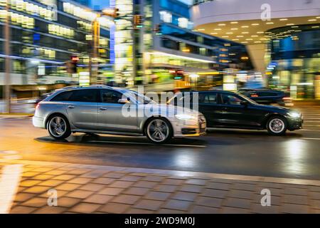 Innerstädtische Straße mit Fahrzeugen, moderne Architektur am Abend. Bewegungsunschärfe. Audi. // 17.01.2024 : Stuttgart, Bade-Württemberg, Deutschland. *** Rue de la ville avec des véhicules, architecture moderne dans le soir Motion blur Audi 17 01 2024 Stuttgart, Baden Württemberg, Allemagne Banque D'Images